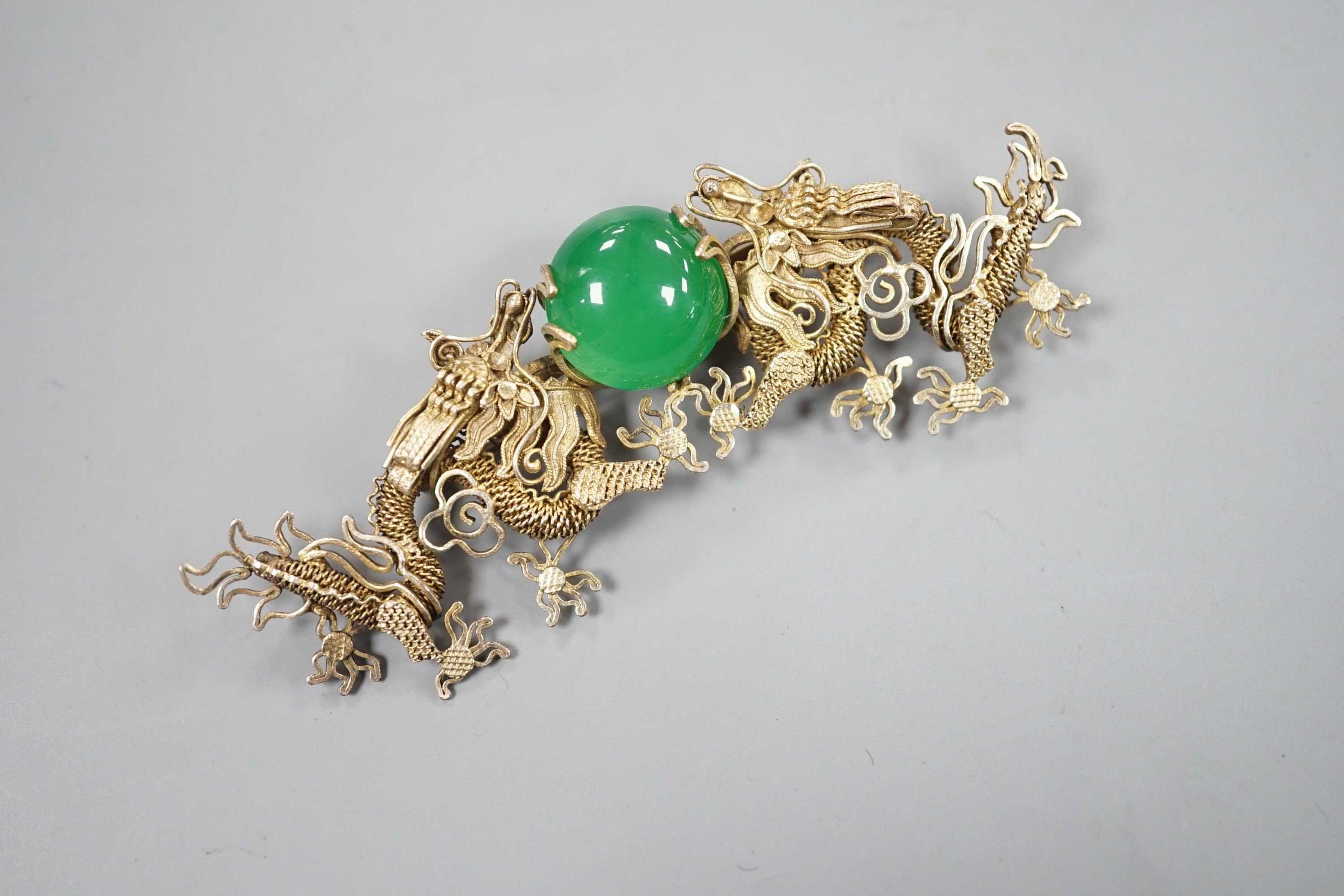 A Chinese gilt white metal and green cabochon stone set filigree dragon brooch, 88mm.